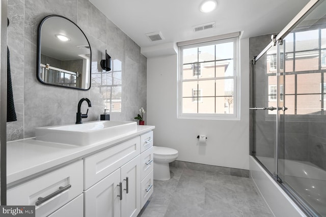 full bathroom with toilet, combined bath / shower with glass door, vanity, and visible vents