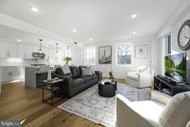 living room featuring baseboards, visible vents, wood finished floors, and recessed lighting