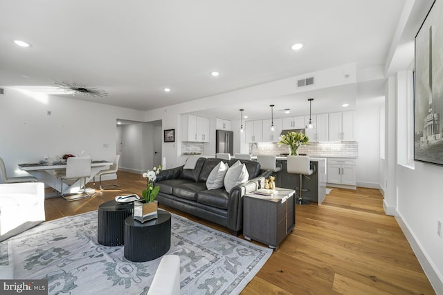 living room with recessed lighting, visible vents, and light wood finished floors