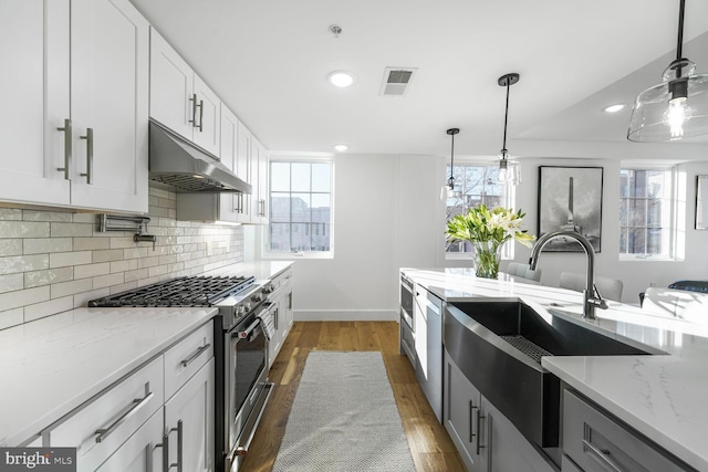 kitchen featuring visible vents, decorative light fixtures, stainless steel appliances, under cabinet range hood, and white cabinetry