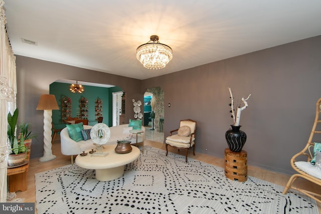 living area featuring a chandelier, wood finished floors, arched walkways, and visible vents