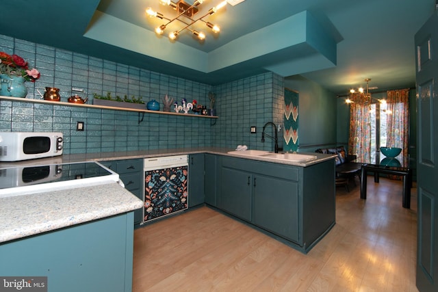 kitchen with a chandelier, white microwave, range with electric cooktop, a sink, and light wood finished floors