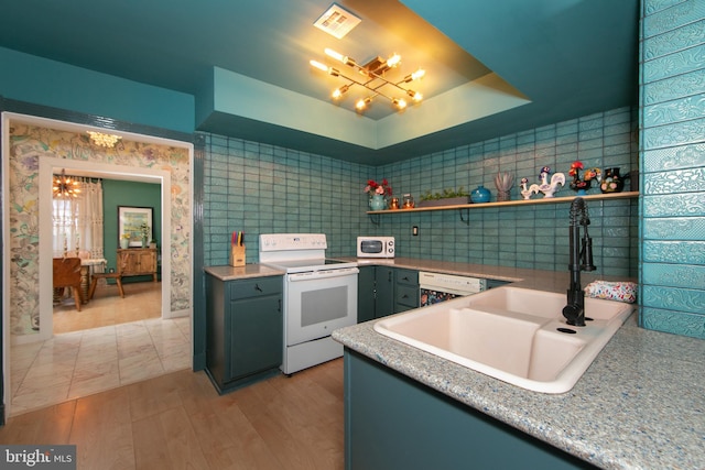 kitchen with light wood-style flooring, white appliances, a sink, visible vents, and a raised ceiling