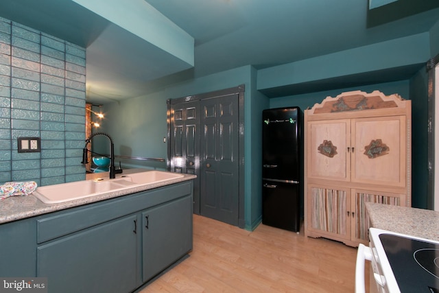 kitchen featuring white electric stove, light countertops, light wood-type flooring, and a sink