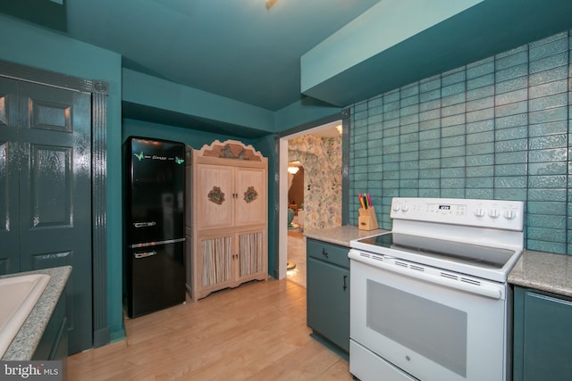 kitchen with white electric stove, light wood-style flooring, light countertops, freestanding refrigerator, and tasteful backsplash