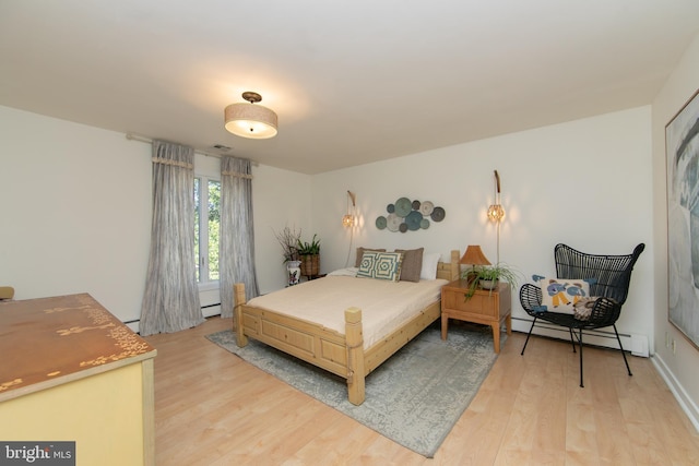 bedroom with light wood-style floors and a baseboard heating unit