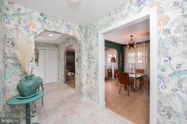 dining area featuring wallpapered walls, baseboards, arched walkways, and a notable chandelier