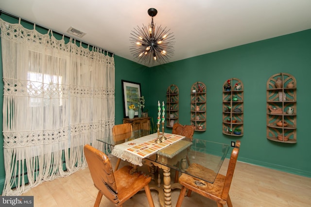 dining space with visible vents, a notable chandelier, and wood finished floors