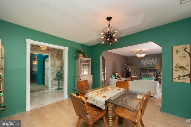 dining space featuring a chandelier, arched walkways, wood finished floors, visible vents, and baseboards