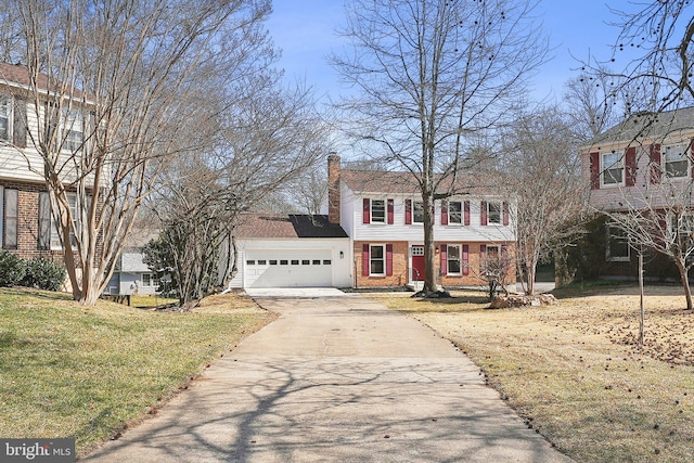 colonial-style house with brick siding, a chimney, concrete driveway, a front yard, and a garage