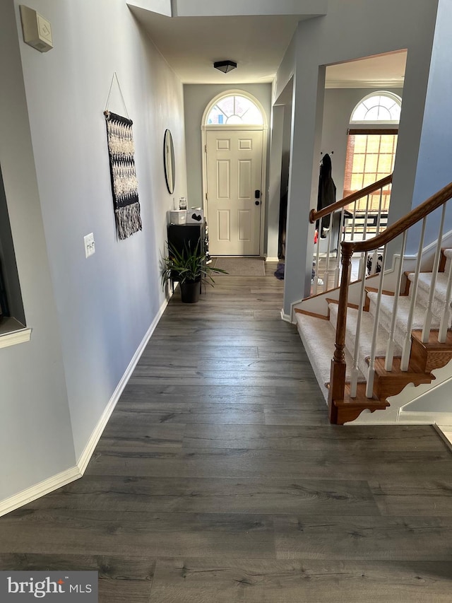 entryway with dark wood-style flooring, baseboards, and stairs