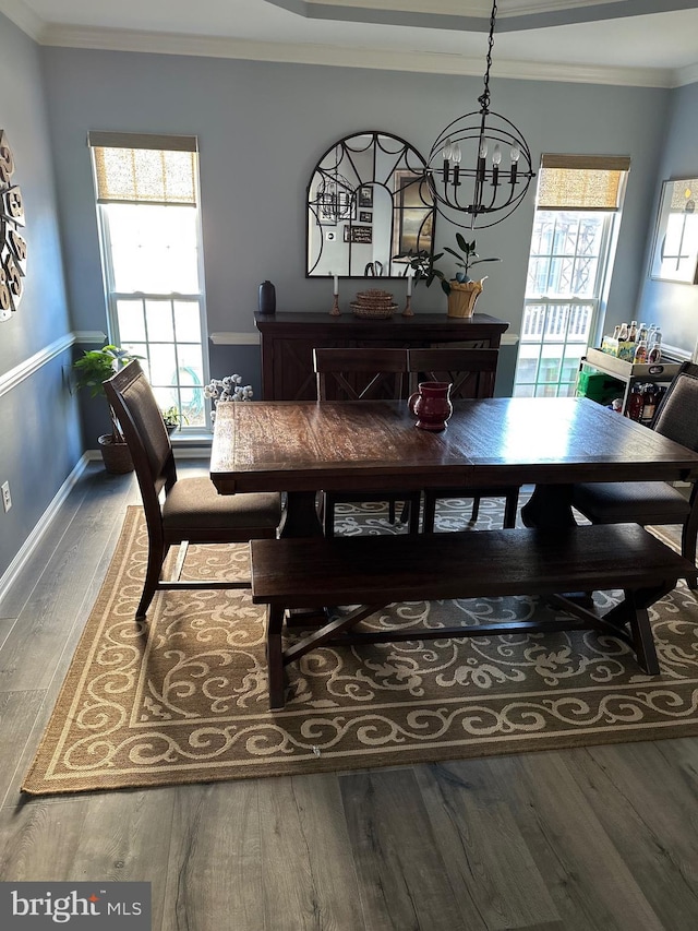 dining space featuring baseboards, ornamental molding, a chandelier, and wood finished floors