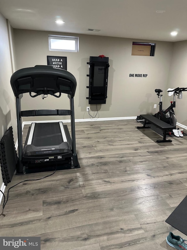 exercise room featuring visible vents, baseboards, and wood finished floors