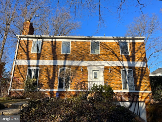 rear view of property featuring brick siding and a chimney