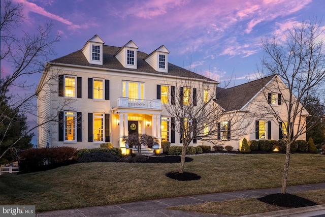 colonial house featuring brick siding, a yard, and a balcony