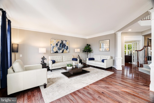 living area featuring ornate columns, stairway, wood finished floors, and ornamental molding