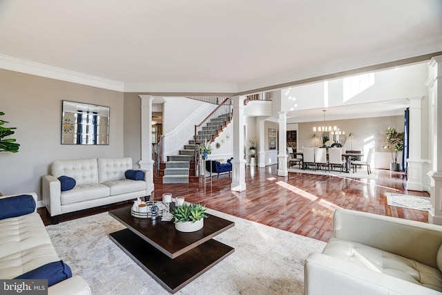 living area featuring ornate columns, stairway, wood finished floors, and ornamental molding