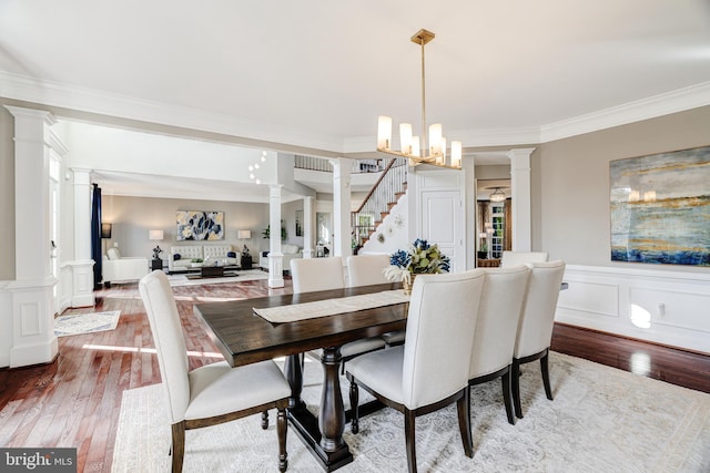 dining area featuring dark wood-type flooring, a decorative wall, ornate columns, and ornamental molding