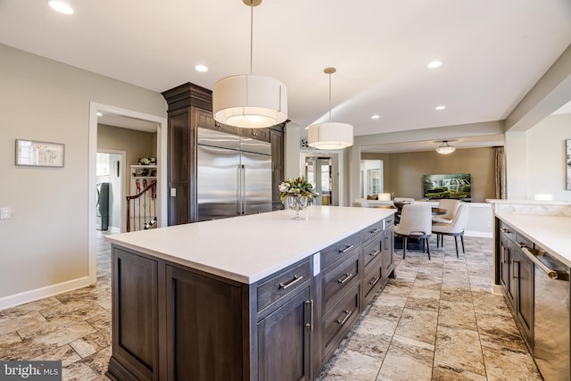 kitchen featuring dark brown cabinetry, stainless steel appliances, light countertops, and a center island