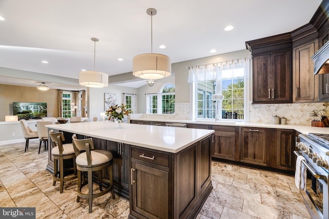 kitchen with a sink, open floor plan, dark brown cabinets, backsplash, and high end range