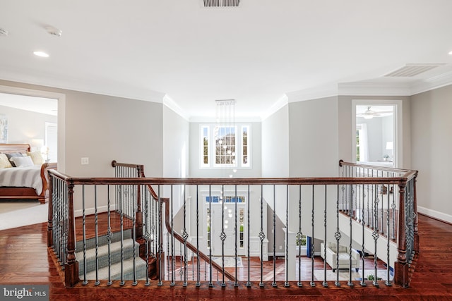 corridor with baseboards, visible vents, wood finished floors, and an upstairs landing