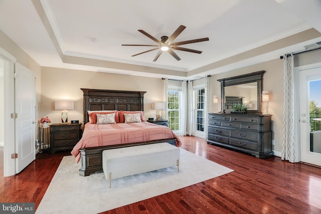 bedroom featuring access to outside, a tray ceiling, wood finished floors, and ornamental molding