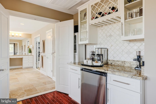 kitchen with glass insert cabinets, stainless steel refrigerator, light stone countertops, white cabinetry, and backsplash