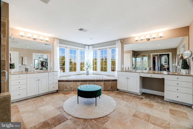 full bathroom featuring two vanities, a garden tub, visible vents, and a shower stall