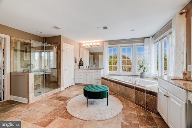 full bathroom with stone tile flooring, visible vents, a stall shower, vanity, and a bath