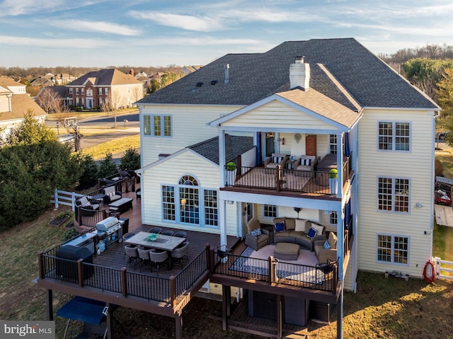 back of property featuring a balcony, an outdoor hangout area, a shingled roof, fence, and a chimney