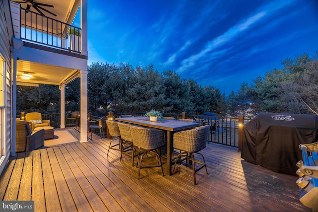 wooden deck featuring a grill, a ceiling fan, and outdoor dining space