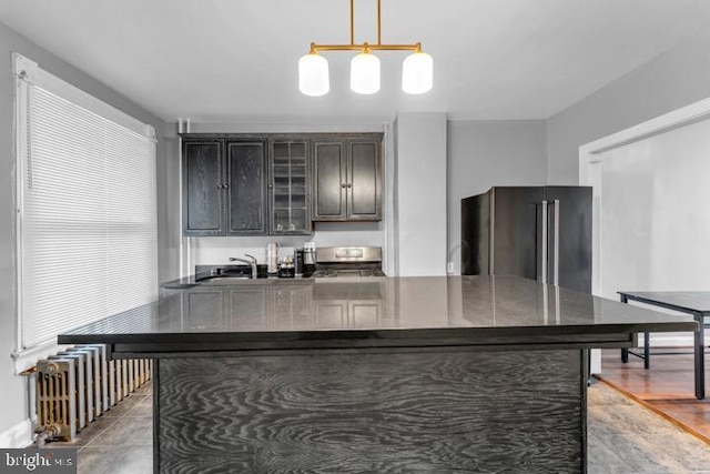 kitchen featuring pendant lighting, dark countertops, glass insert cabinets, high quality fridge, and dark brown cabinetry