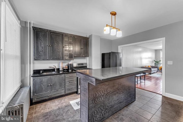 kitchen featuring dark brown cabinetry, high end refrigerator, a sink, a kitchen island, and dark countertops