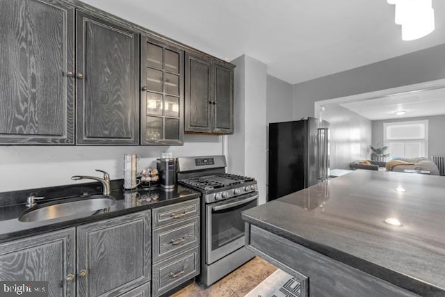 kitchen with dark countertops, high quality fridge, a sink, dark brown cabinets, and gas range