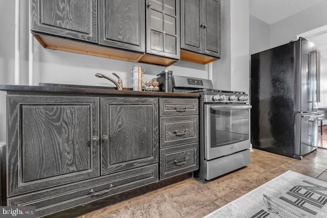 kitchen featuring freestanding refrigerator, dark countertops, and stainless steel range with gas cooktop