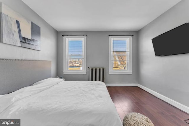 bedroom with baseboards, multiple windows, dark wood-style floors, and radiator