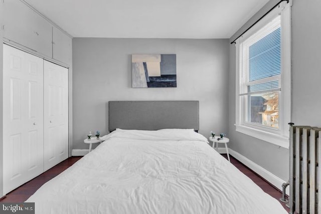 bedroom featuring radiator, dark wood-style floors, baseboards, and a closet