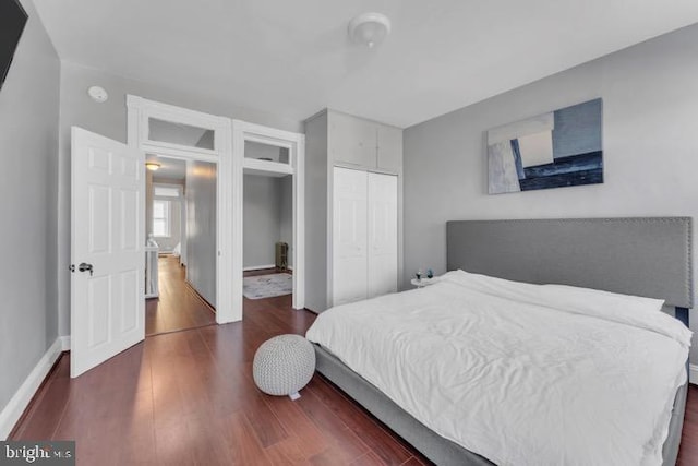 bedroom featuring dark wood-style floors, a closet, and baseboards