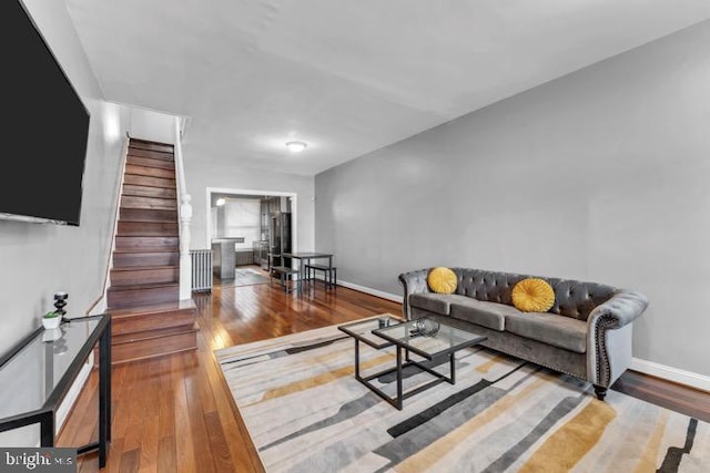 living area with baseboards, stairway, and wood finished floors