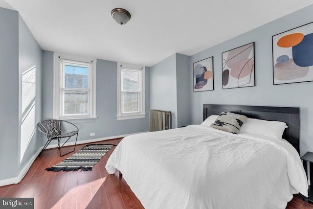 bedroom with radiator heating unit, baseboards, and dark wood finished floors