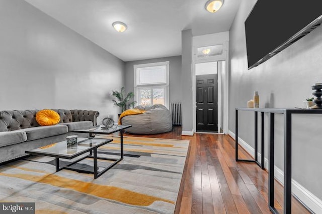 living area with baseboards, radiator heating unit, and wood finished floors