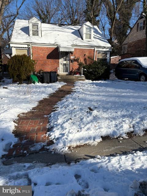 snow covered property featuring brick siding