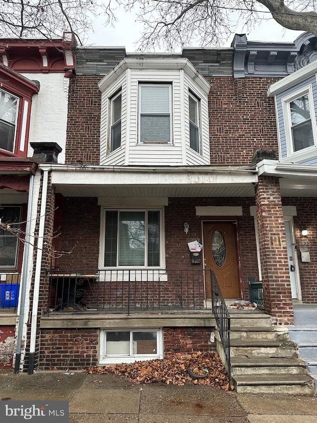 multi unit property with a porch and brick siding