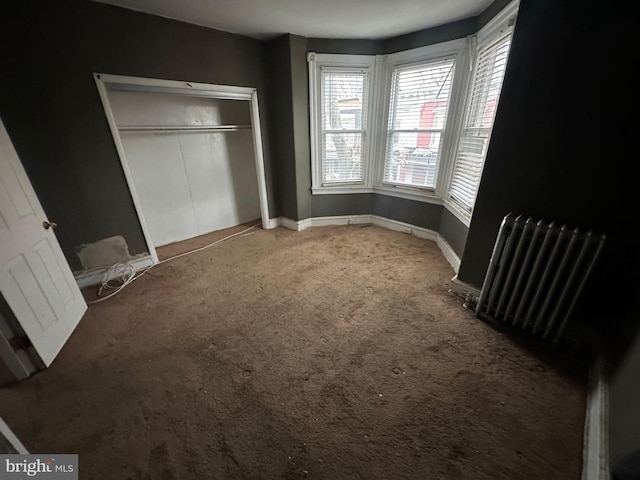 carpeted bedroom with baseboards, a closet, and radiator