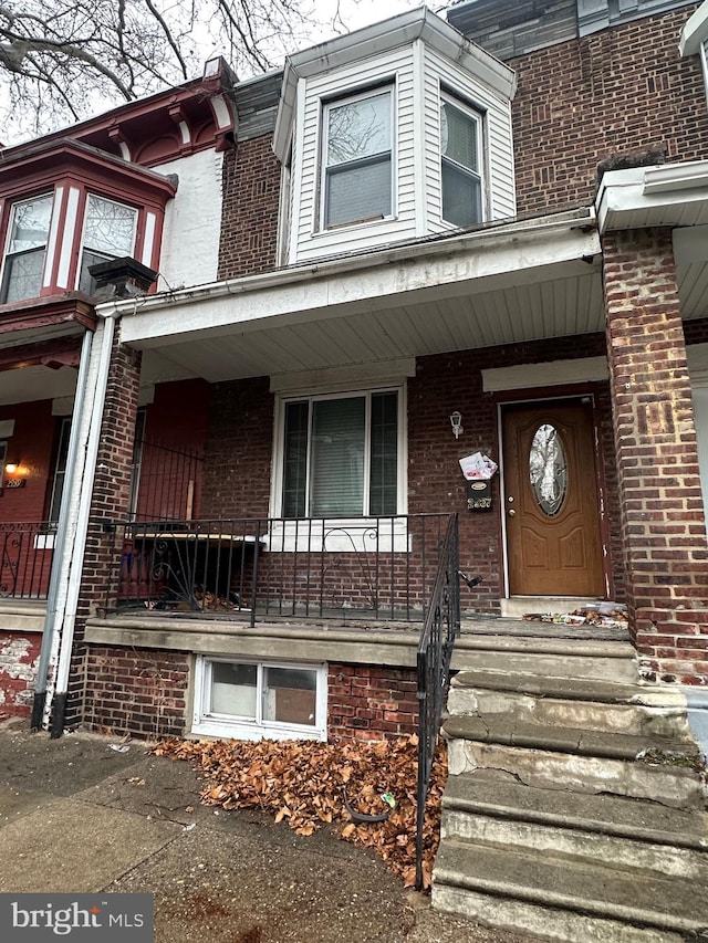 view of exterior entry featuring covered porch and brick siding