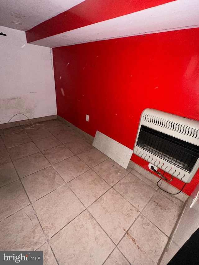 additional living space with baseboards, tile patterned floors, and heating unit