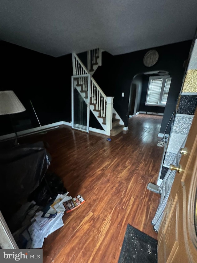 foyer entrance with stairway, arched walkways, and dark wood-style flooring