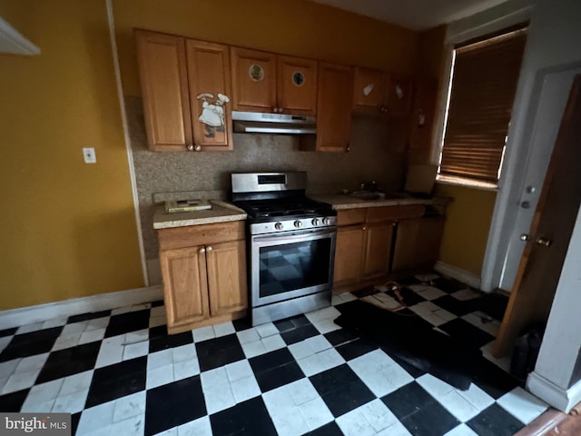 kitchen featuring light floors, stainless steel range with gas cooktop, and under cabinet range hood