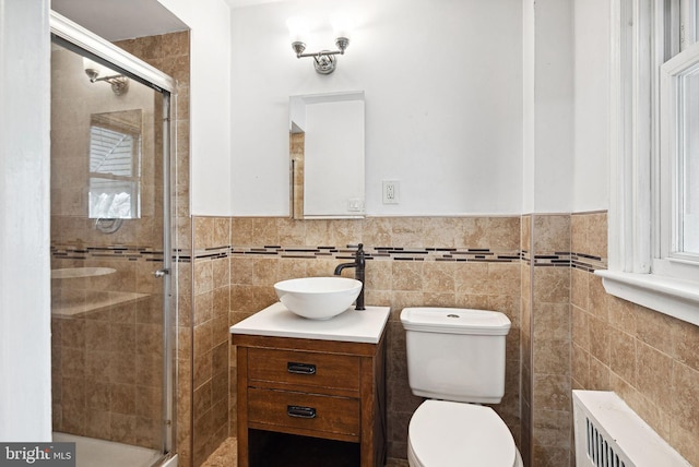 bathroom with radiator, a stall shower, tile walls, and vanity