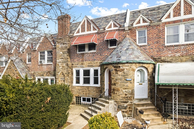 english style home with a high end roof, stone siding, and entry steps